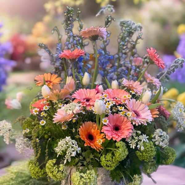 Mixed pink and orange flowers in a rustic vase