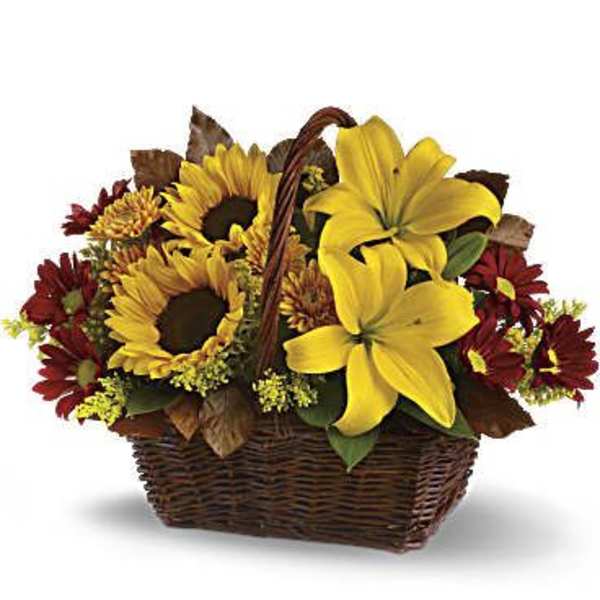 Basket arrangement with yellow lilies, sunflowers, and red daisies