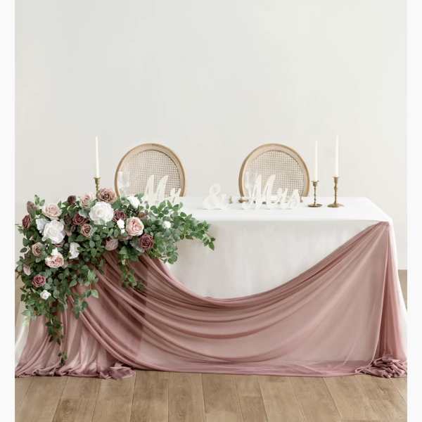 Wedding table with pink floral arrangement and draped blush fabric