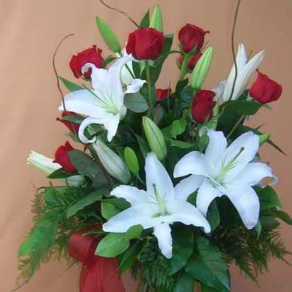 Red roses and white lilies in a glass vase with a red ribbon