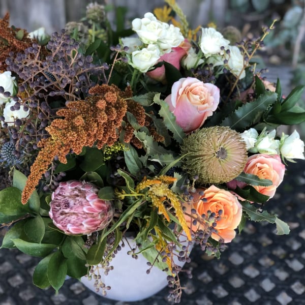 Mixed bouquet of peach and white roses in a white vase