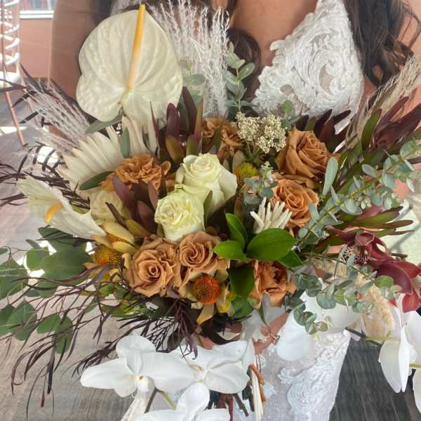 Bride holding a large bouquet with white orchids and tan roses
