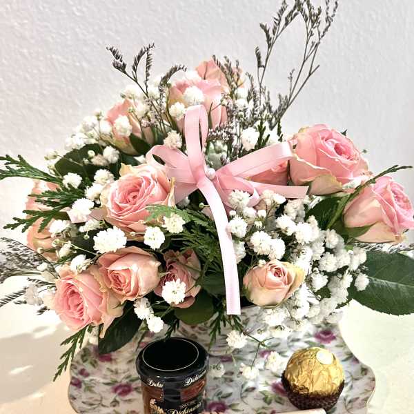 Pink rose bouquet with baby's breath, ribbon, and chocolates on a floral tray