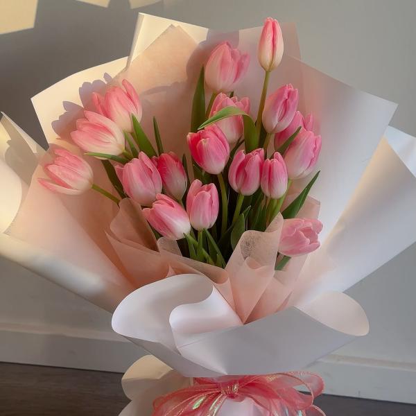 Pink tulip bouquet wrapped in white and blush paper with a pink ribbon