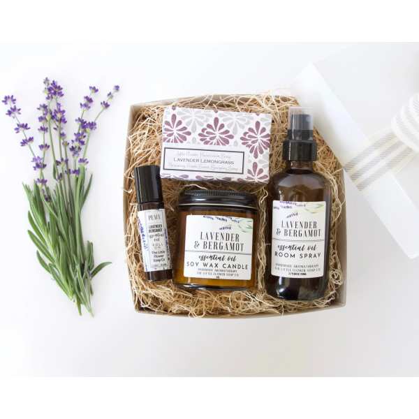 Lavender sprigs beside a gift box with soap, candle, spray, and oil