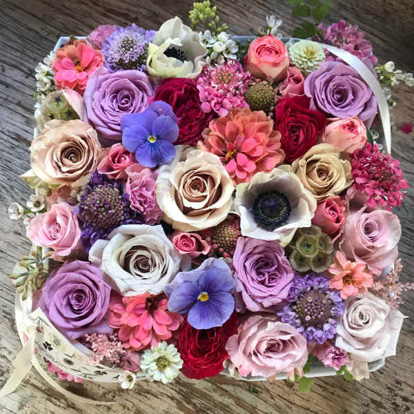 Round bouquet of pastel and bright mixed flowers in a white box