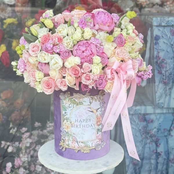Pink and white rose bouquet in a purple birthday box with a ribbon