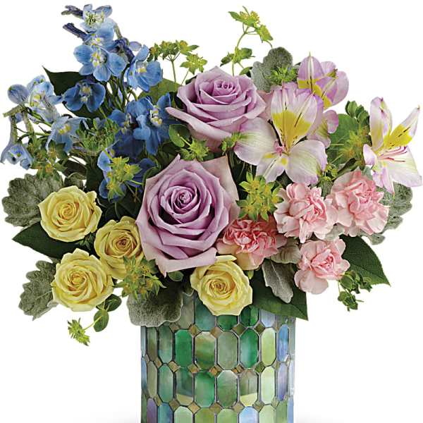 Mixed bouquet of roses, lilies, and blue flowers in a mosaic vase
