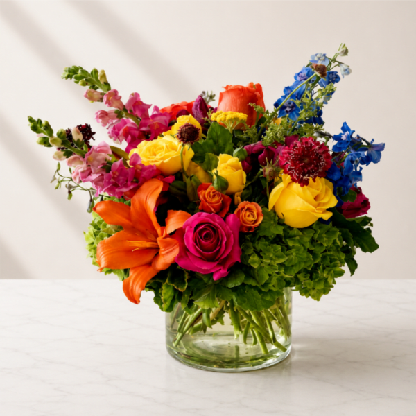 Colorful mixed bouquet in a clear glass vase with roses and lilies