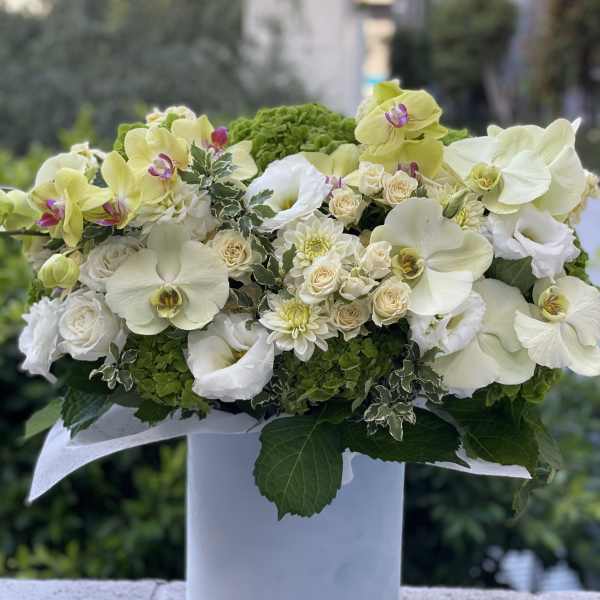 White and pale green floral arrangement in a white vase
