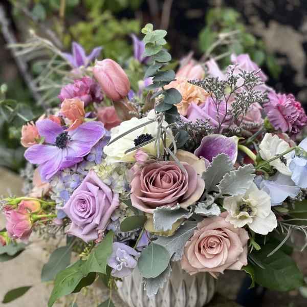 Pastel bouquet of roses, anemones, and tulips in a white vase