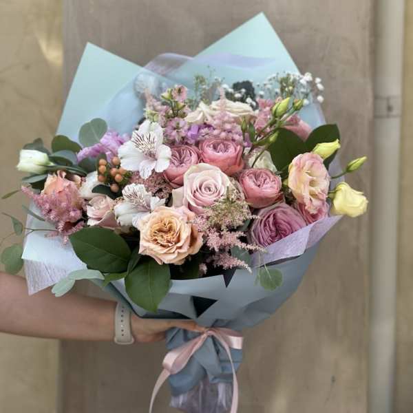 Handheld bouquet of pink and white roses with pastel wrapping
