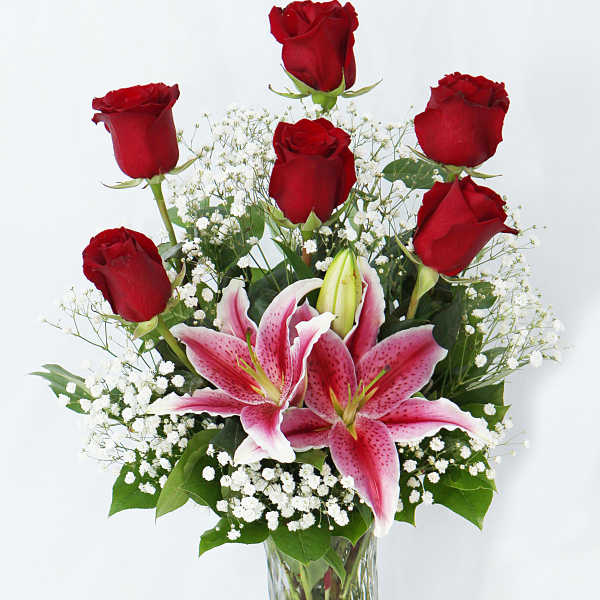 Red roses and pink lilies in a clear glass vase