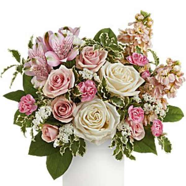 Pink and white roses in a white vase with mixed filler flowers
