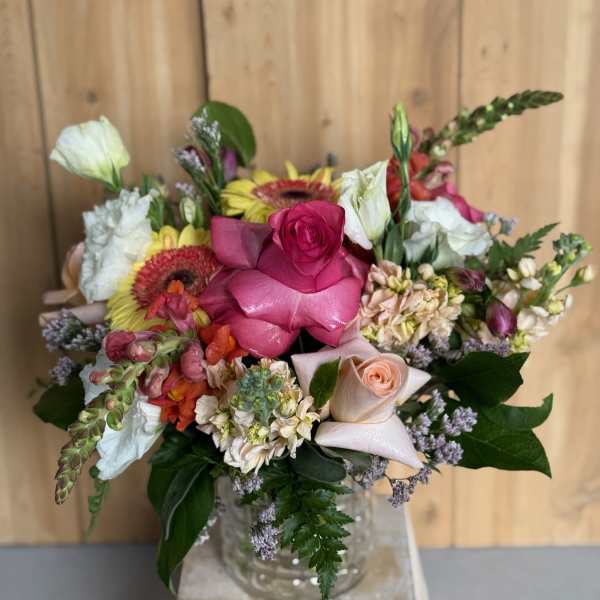 Mixed bouquet with pink roses, white blooms, and gerbera daisies in a glass vase