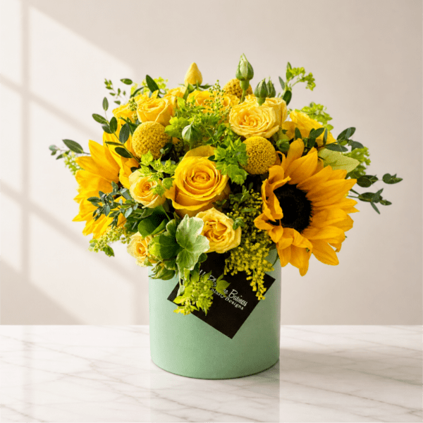 Yellow roses and sunflowers arranged in a mint green box