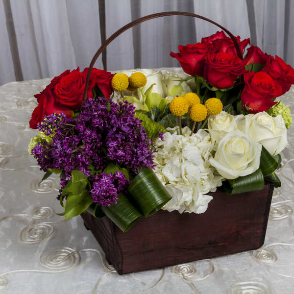 Basket arrangement of red and white roses with purple flowers