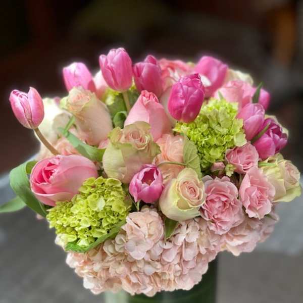Pink tulips and roses arranged in a glass vase