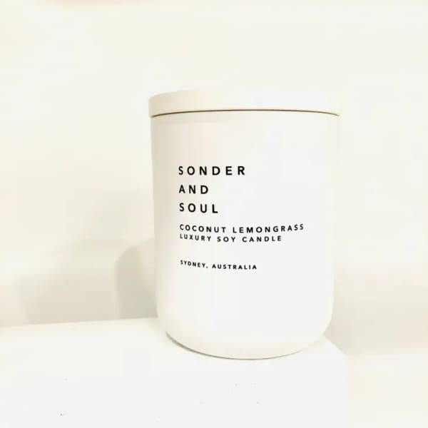 White scented candle in a cylindrical container with black text