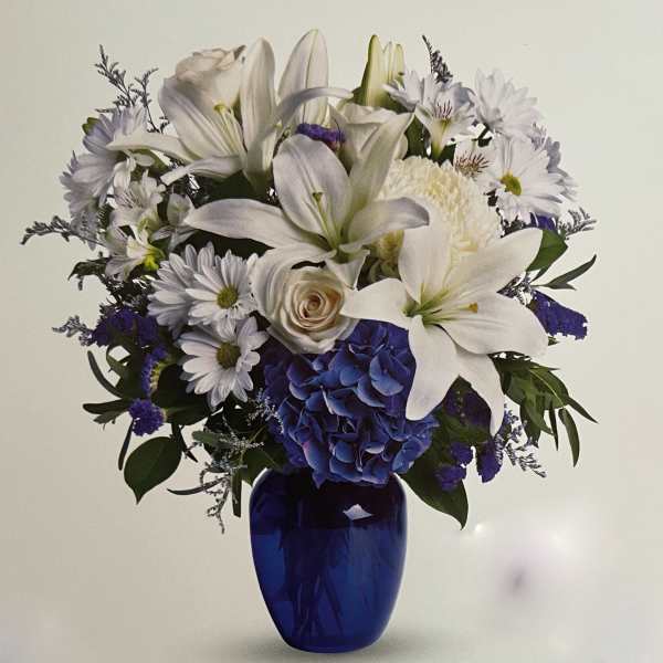 White lilies and daisies with blue hydrangea in a cobalt vase