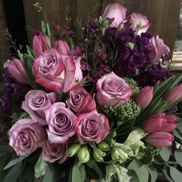 Pink and lavender roses with tulips in a spotted vase