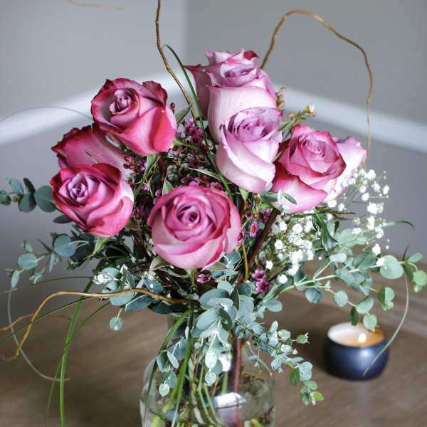 Pink roses arranged in a glass vase with airy filler flowers