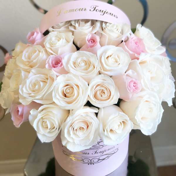 Bouquet of white and pale pink roses in a pink hatbox
