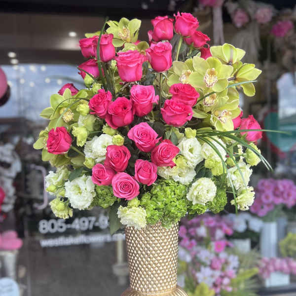 Pink roses and green orchids arranged in a gold vase