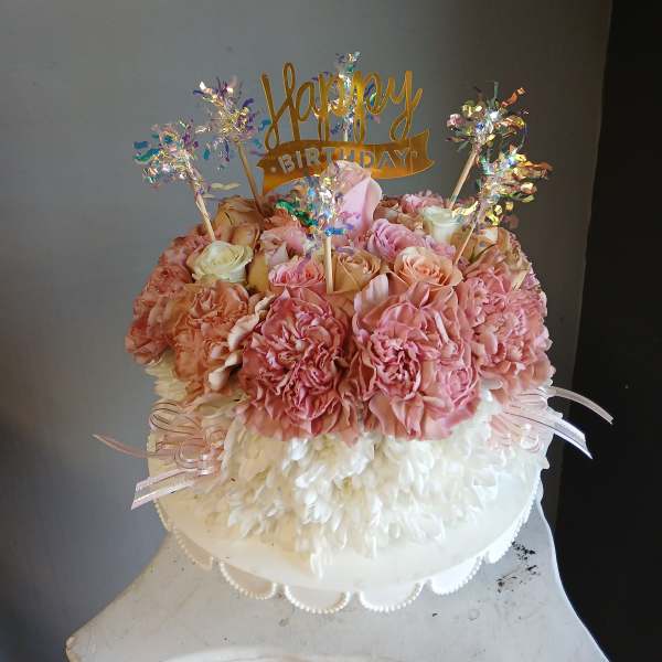 Pink and white floral cake with a happy birthday topper
