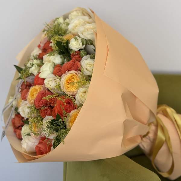Bouquet of cream, coral, and yellow roses wrapped in peach paper
