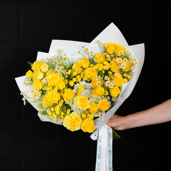Yellow rose bouquet with small white daisies wrapped in white paper