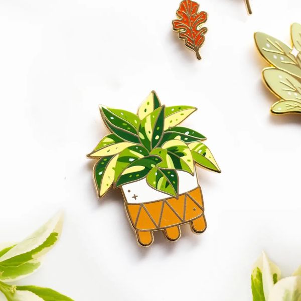 Enamel pin of a potted leafy plant on a white background