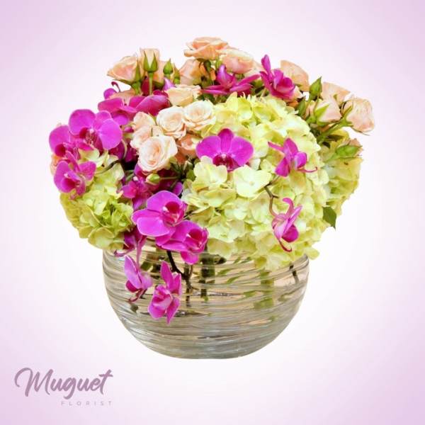 Pink orchids and pale hydrangeas in a clear glass bowl vase