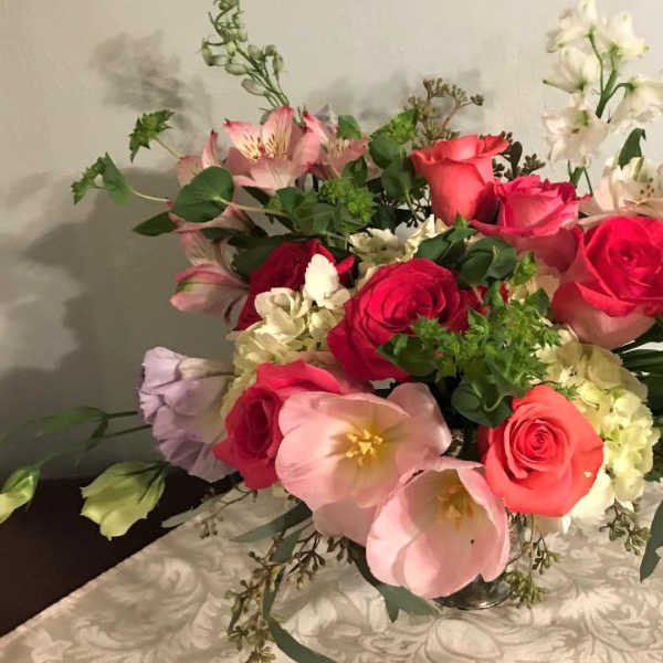 Mixed bouquet of roses, lilies, and alstroemeria in a glass vase