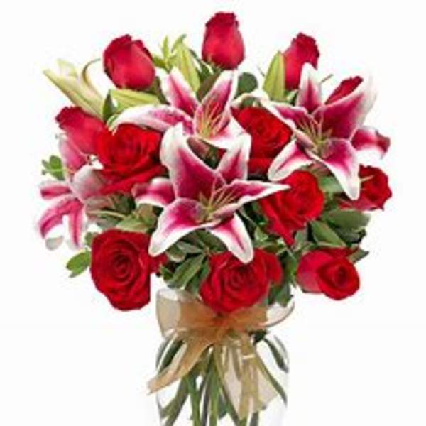 Bouquet of red roses and pink lilies in a clear glass vase
