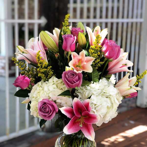 Bouquet of pink lilies, roses, and white hydrangeas in a glass vase