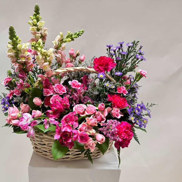 Basket arrangement of pink flowers with purple accents