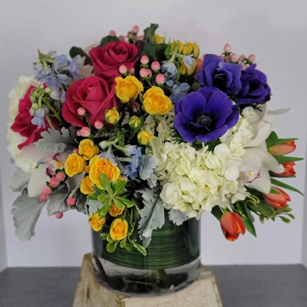 Mixed bouquet of roses, hydrangeas, and tulips in a glass vase