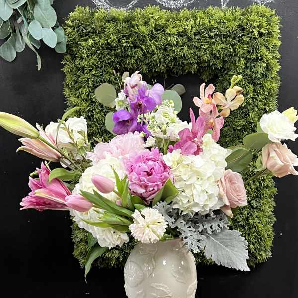 Pink, white, and purple flowers arranged in a white vase