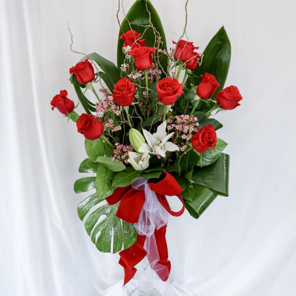 Tall bouquet of red roses with white flowers in a glass vase