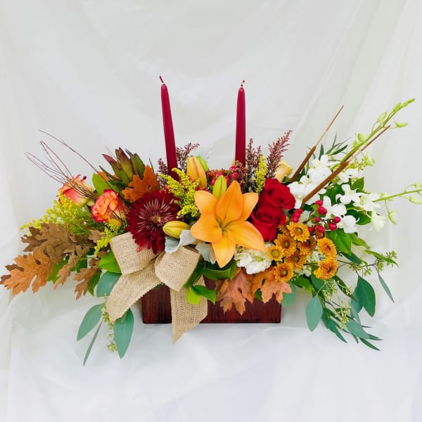 Autumn floral centerpiece with lilies, roses, and candles in a wooden box