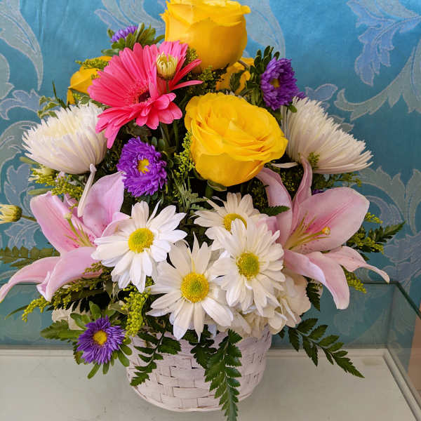 Basket arrangement with yellow roses, pink lilies, and white daisies