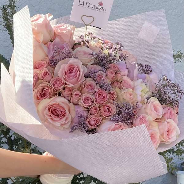 Large bouquet of pink roses wrapped in pale pink paper