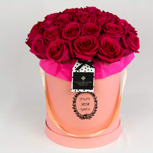 Bouquet of deep pink roses in a pink hatbox