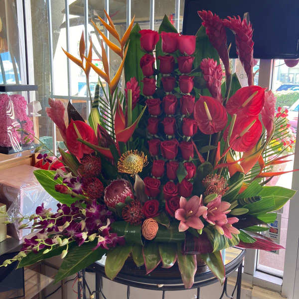 Large tropical arrangement with red roses, anthuriums, orchids, and bird-of-paradise