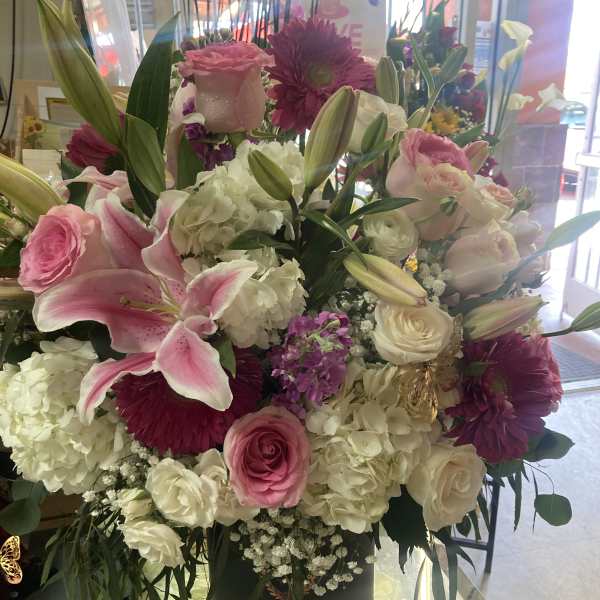Large pink and white floral arrangement in a black container