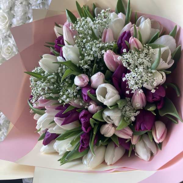 Bouquet of pink, white, and purple tulips wrapped in pastel paper