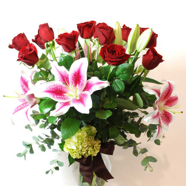 Bouquet of red roses and pink lilies in a clear glass vase