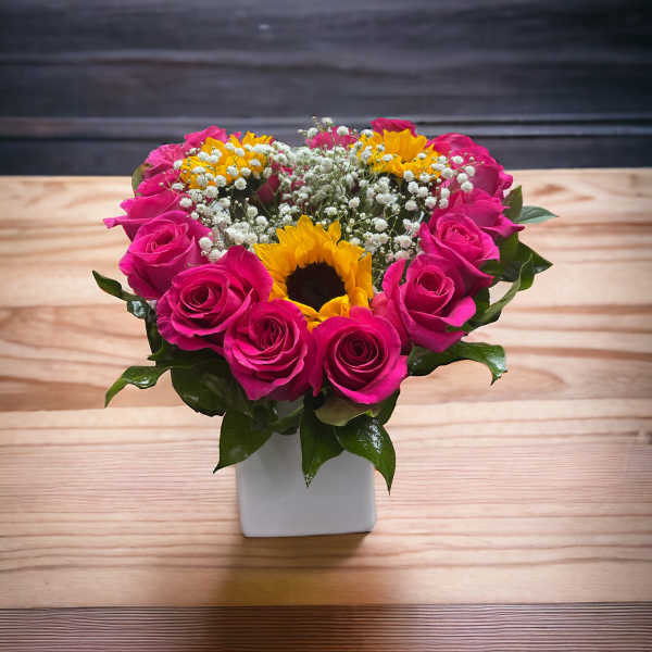 Pink roses and sunflowers in a white square vase
