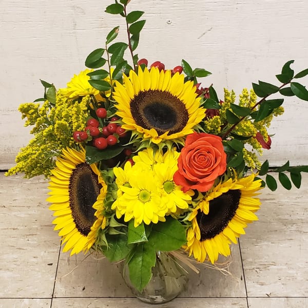 Sunflower and orange rose arrangement in a glass vase